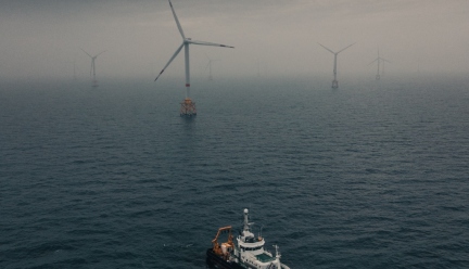 picture of a sea with a ship on the foreground and wind turbine on the background
