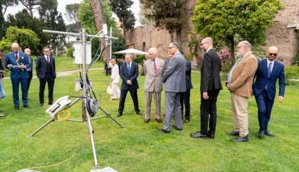 group of people standing around an eddycovariance instrument on green grass 